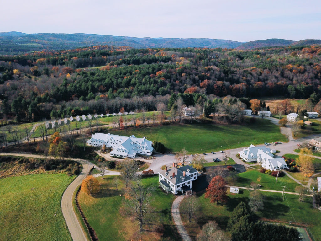 Aerial view of a cluster of white buildings on green rolling hills.