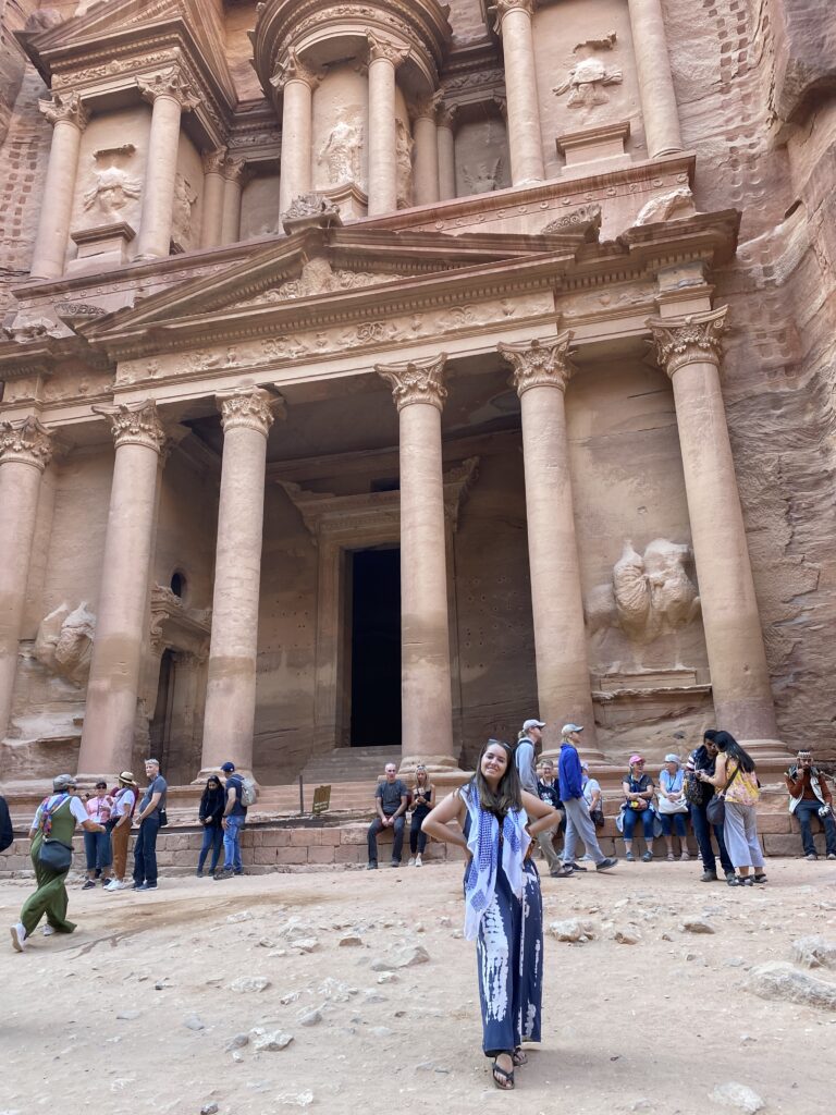 A young adult wearing a long scarf poses in Petra, Jordan.