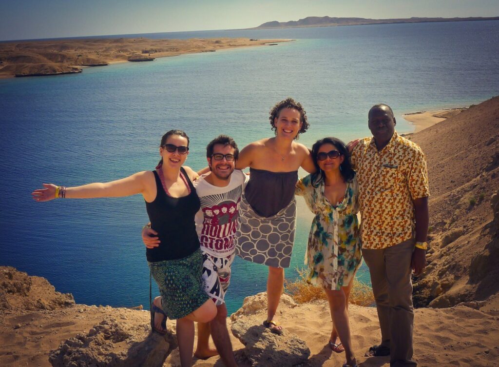 Five adults pose together on a hill overlooking the Red Sea.